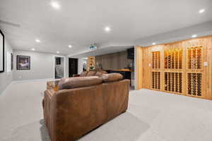 Living area with light colored carpet, recessed lighting, and bar with sink