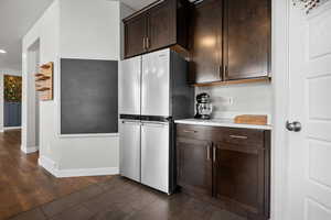 Kitchen featuring dark wood finish cabinetry, freestanding refrigerator, and dark tile patterned flooring
