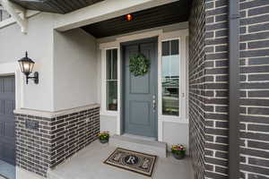 Property entrance with a porch, stucco siding, and a garage