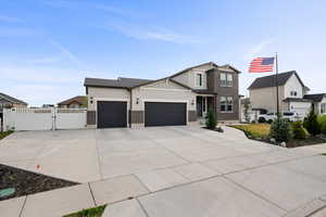 View of front of house with a gate, a garage, driveway, brick siding, and stucco siding