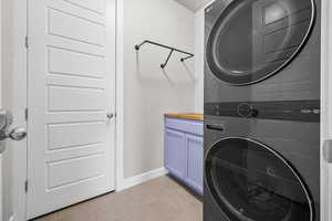 Laundry room with stacked washer and clothes dryer and cabinet space