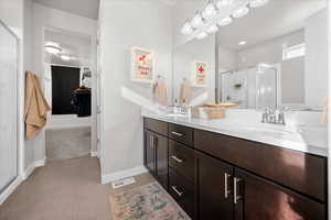 Bathroom featuring a shower stall, double vanity, and a spacious closet