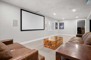 Cinema room with light colored carpet, a textured ceiling, and recessed lighting