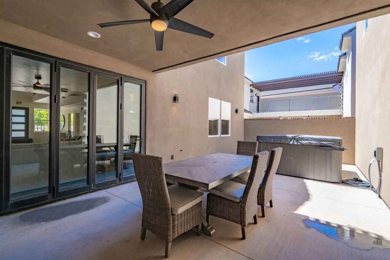 View of patio with a jacuzzi, outdoor dining space, and ceiling fan