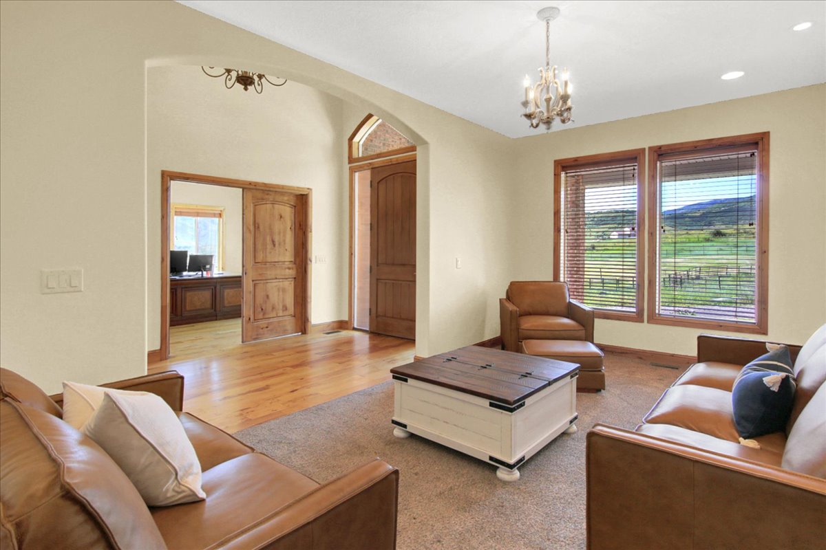 Living room featuring suspended lighting, arched walkways, and light wood-style flooring