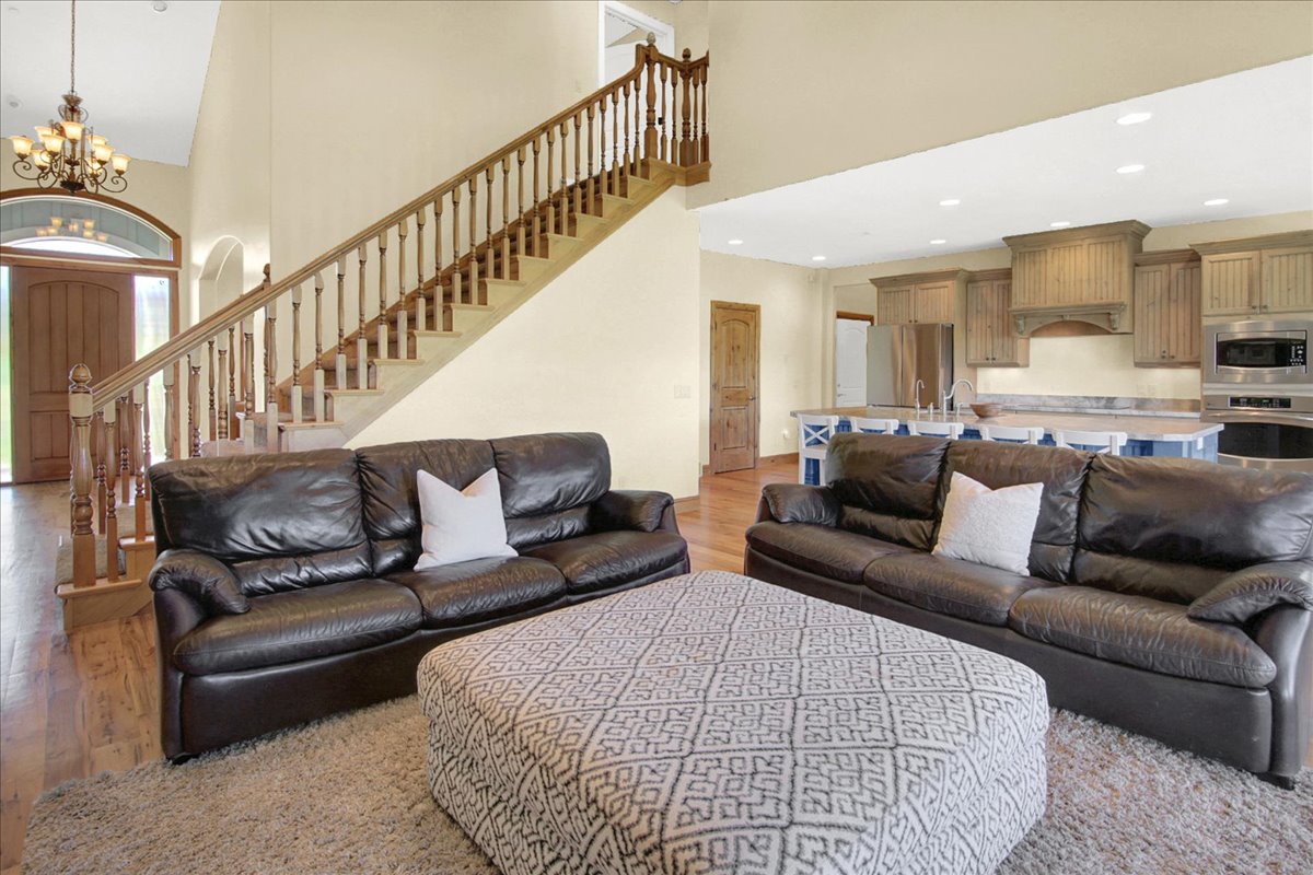 Living room with a high ceiling, suspended lighting, and light wood-style floors
