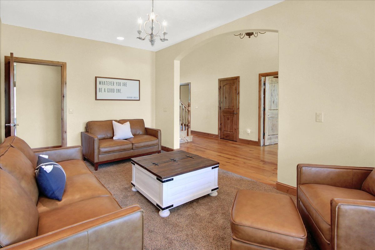 Living room with arched walkways, light carpet, and hanging lights
