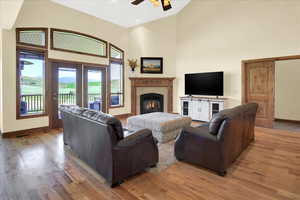 Living room featuring light wood-style flooring, ceiling fan, a fireplace, and lofted ceiling