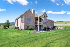 Back of house featuring brick siding, a patio, a chimney, and a view of countryside