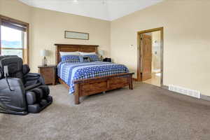 Master Bedroom featuring light colored carpet, lofted ceiling, and ensuite bath