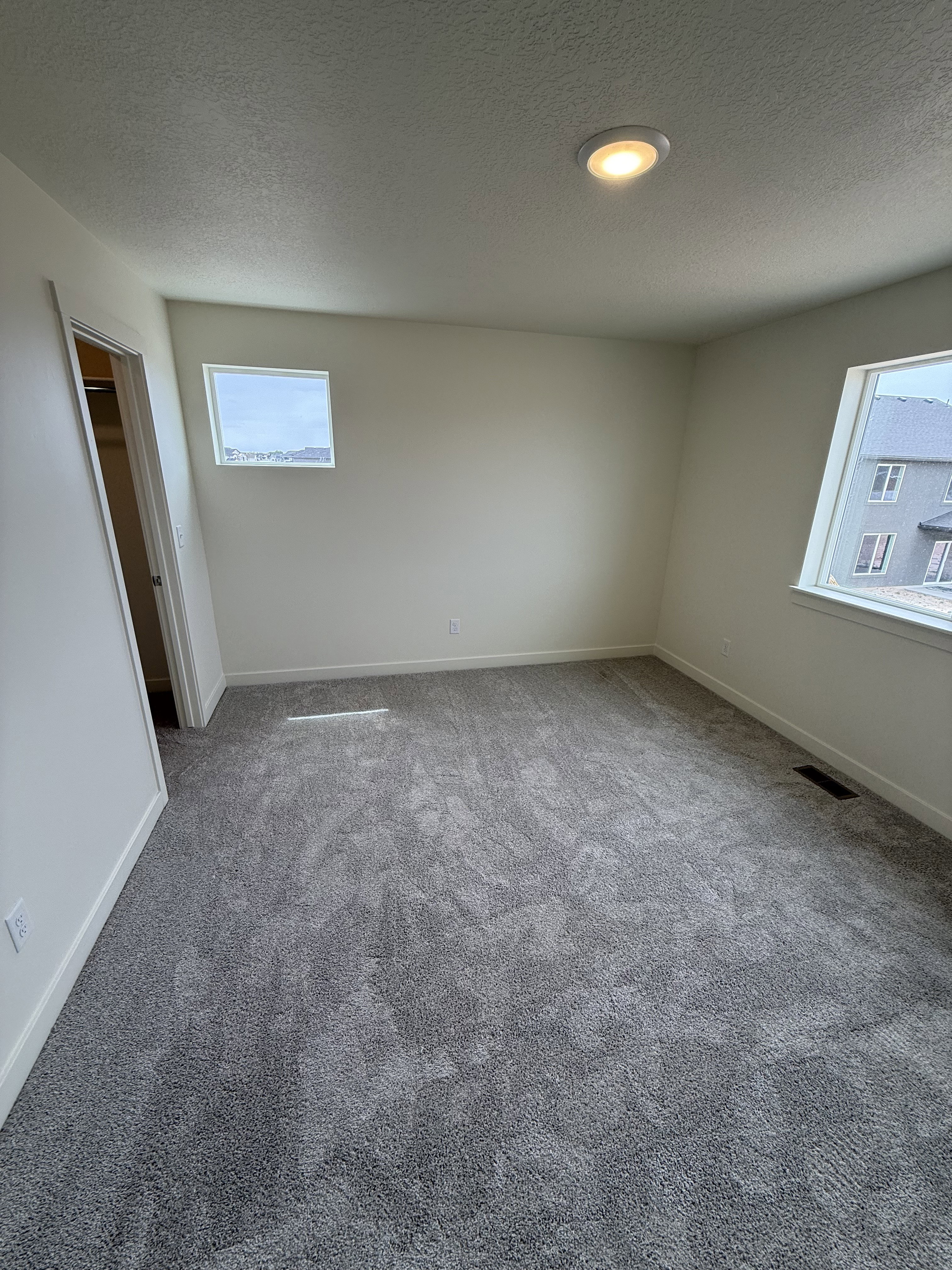 Spacious room featuring neutral carpeting, recessed ceiling lighting, and two windows providing exterior views