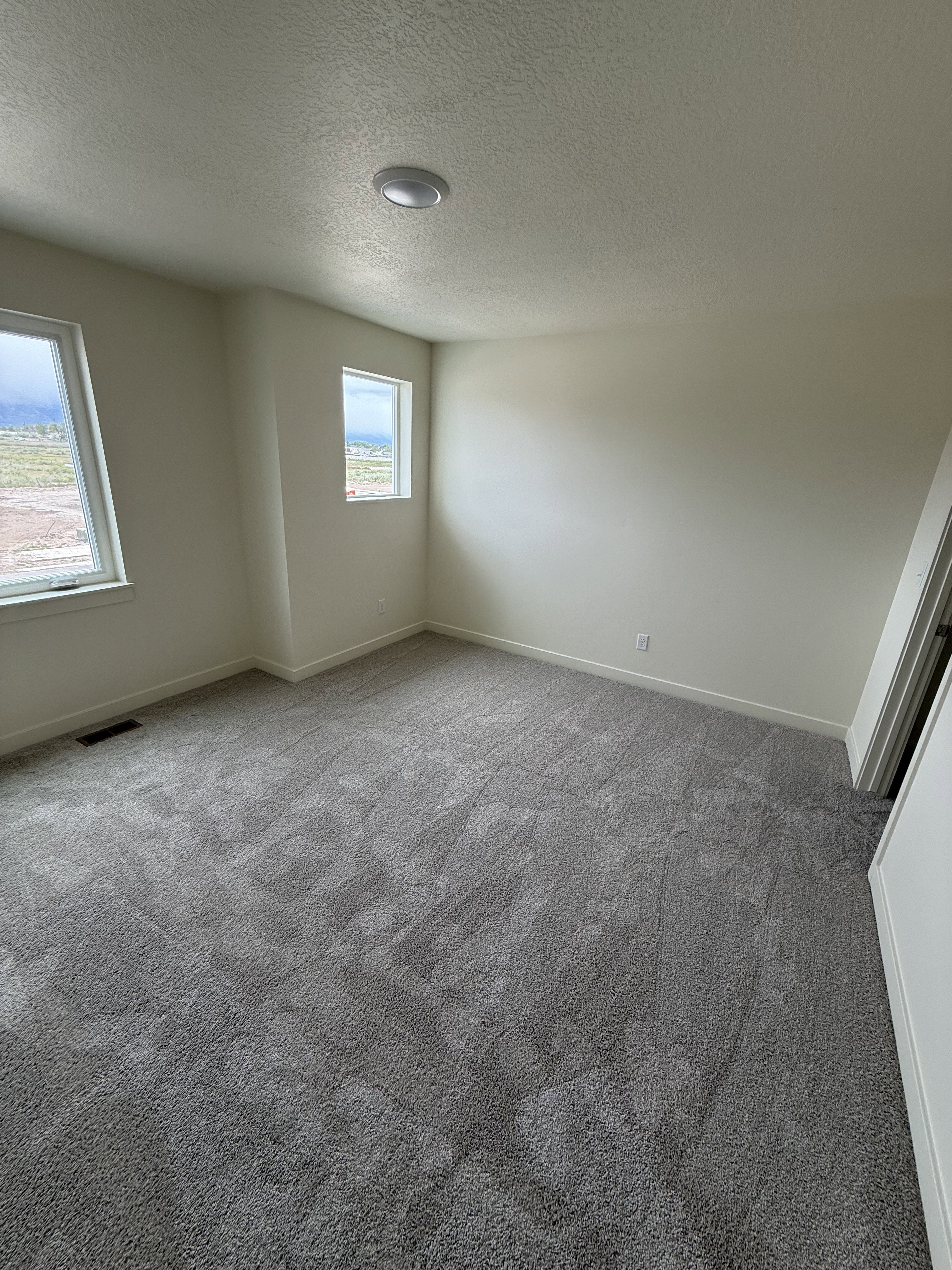 Neutral-toned room featuring a gray carpeted floor, white baseboards, and light-colored walls