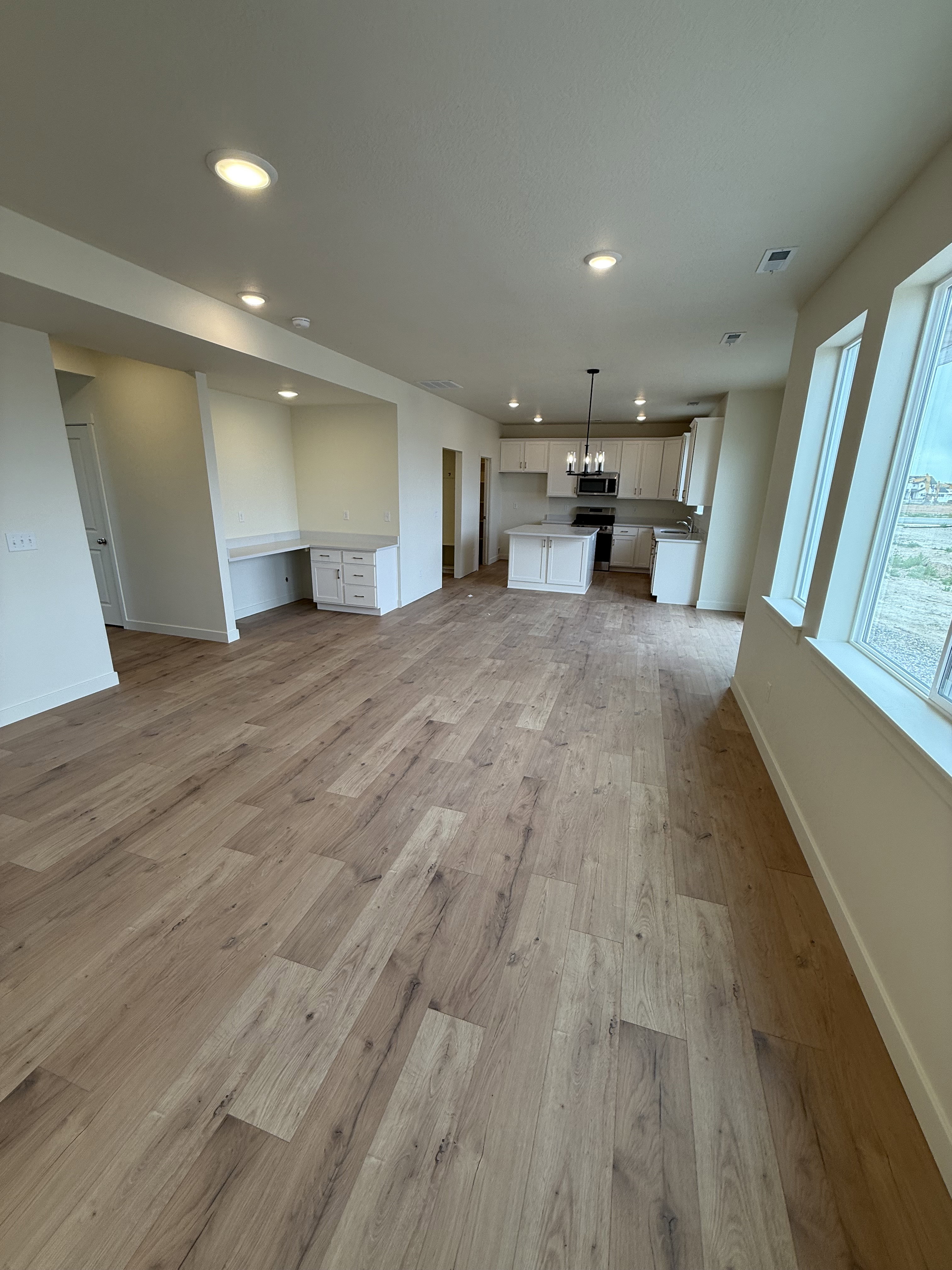 Spacious open-concept area featuring wood-finish flooring, recessed lighting, and a built-in desk with cabinetry