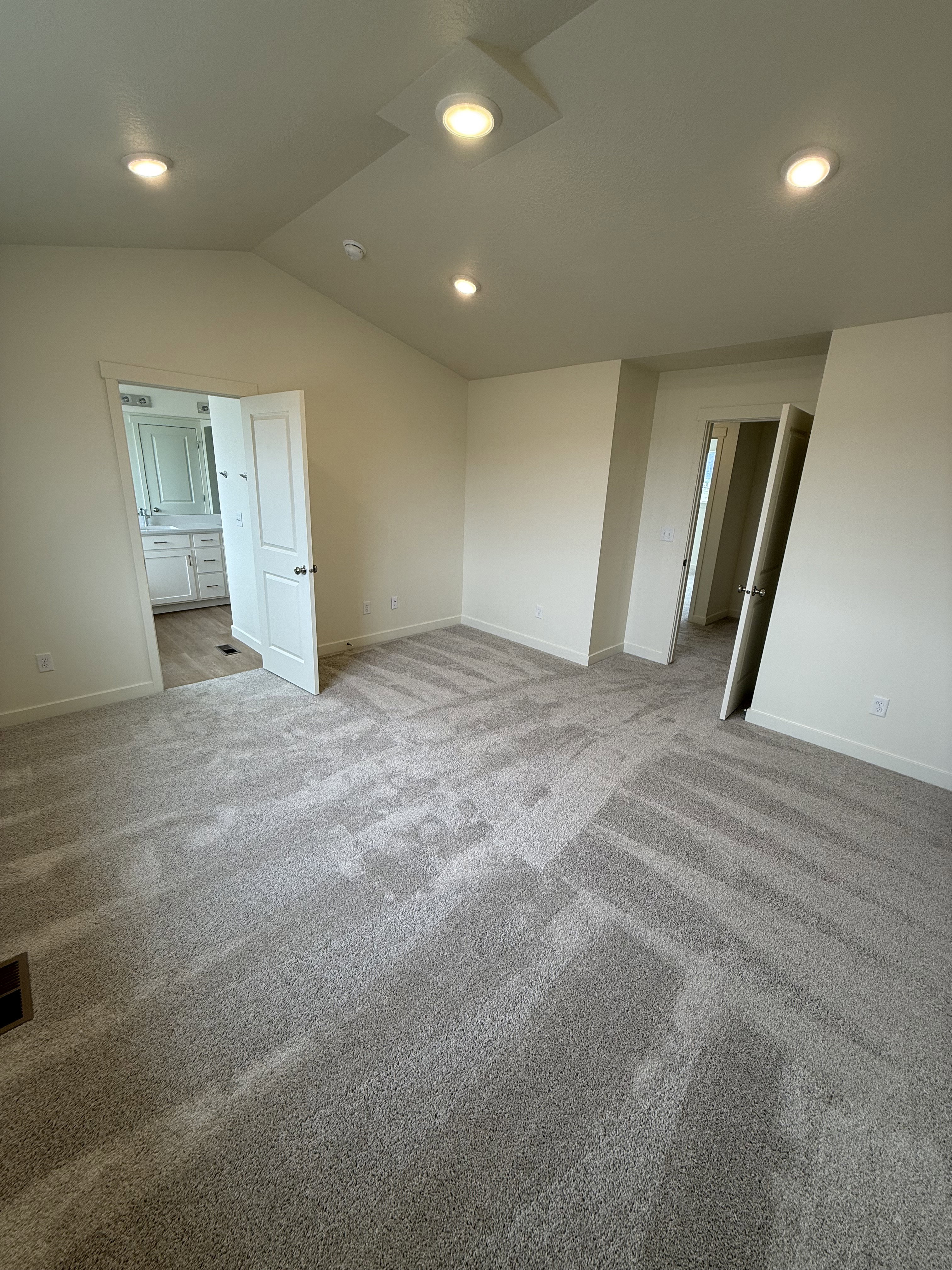 Spacious room featuring vaulted ceilings, recessed lighting, neutral wall tones, and plush carpet flooring