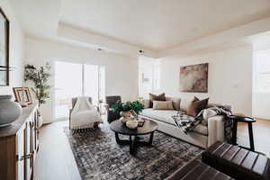 Living room with healthy amount of natural light, recessed lighting, light wood-style flooring, and a tray ceiling