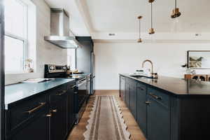 Kitchen featuring stainless steel appliances, dark cabinets, a kitchen island with sink, decorative light fixtures, and a kitchen breakfast bar