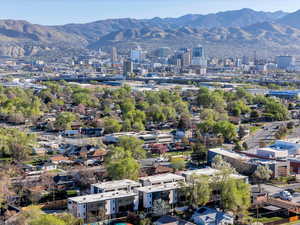 Aerial view of property and surrounding area featuring mountains and nearby urban area