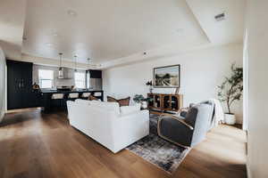 Living room with dark wood-style flooring, recessed lighting, and a raised ceiling