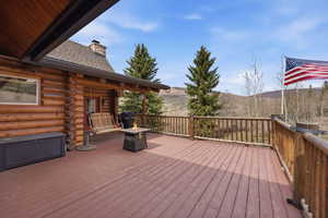 Wooden deck featuring a fire pit, a mountain view, and area for grilling