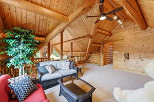 Living area featuring carpet floors, wood walls, rustic walls, a ceiling fan, and a wood ceiling with exposed beams