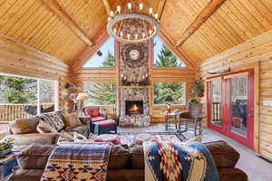 Living area featuring a chandelier, log walls, healthy amount of natural light, a fireplace, and carpet floors