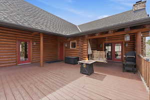 Wooden terrace with a fire pit, area for grilling, and french doors