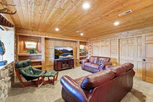 Living area featuring wooden ceiling, recessed lighting, light carpet, and wooden walls