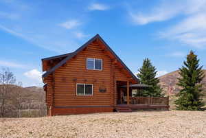 Rear view of house with log siding and a deck with mountain view