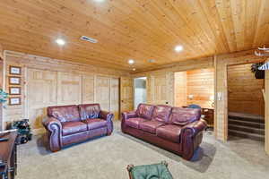 Living room with wooden ceiling, carpet flooring, recessed lighting, and wooden walls