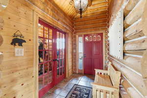 Foyer featuring french doors, stone tile floors, and wood ceiling