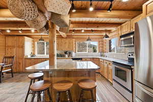 Kitchen featuring stainless steel appliances, track lighting, backsplash, a wooden ceiling with exposed beams, and light countertops