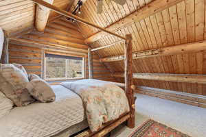Carpeted bedroom with rustic walls, vaulted ceiling with beams, and wooden ceiling