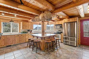 Kitchen with stainless steel appliances, tasteful backsplash, a breakfast bar, light wood finish cabinetry, and stone tile flooring