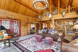 Carpeted living area with log walls and a high wooden beamed ceiling