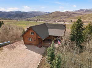 View of front of home with log siding, roof with shingles, a mountain view, a chimney, and a view of rural / pastoral area