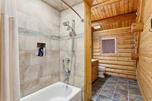 Bathroom featuring log walls, shower / bathtub combination with curtain, a wooden ceiling with exposed beams, and vanity