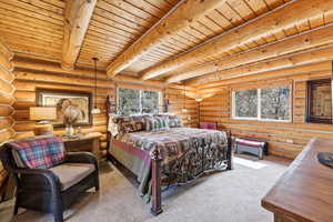 Bedroom featuring light colored carpet, rustic walls, and a wooden ceiling with exposed beams
