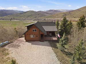 View of front of house featuring log siding, a deck with mountain view, and a view of rural / pastoral area