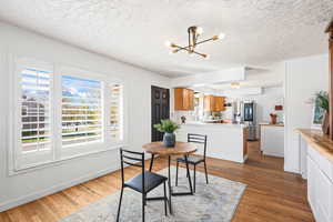 Dining area featuring dark wood-type flooring, suspended lighting, and a textured ceiling