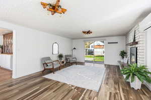 Sitting room with dark wood-type flooring, a fireplace, and a textured ceiling