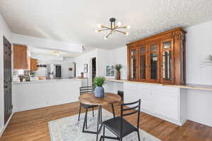 Dining space with arched walkways, a textured ceiling, dark wood finished floors, and a chandelier
