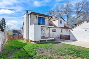 Rear view of house featuring a balcony, a patio area, a fenced backyard, and a chimney