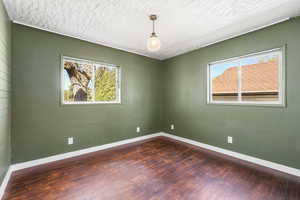 Unfurnished room with dark wood-type flooring and a textured ceiling