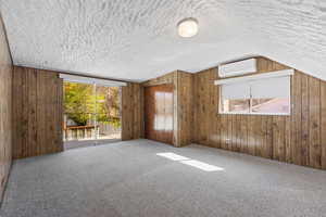 Spare room featuring carpet, a textured ceiling, and wood walls