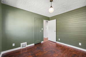Empty room featuring dark wood finished floors and a textured ceiling