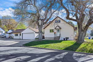 View of front of property featuring a front yard, an outbuilding, a garage, and concrete driveway