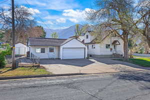 View of front of house with an outdoor structure, driveway, a mountain view, and a garage