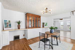 Dining area with a textured ceiling, dark wood finished floors, and a chandelier