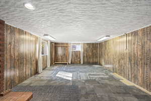 Carpeted spare room featuring a textured ceiling and wooden walls