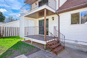 View of exterior entry with a shingled roof and a deck